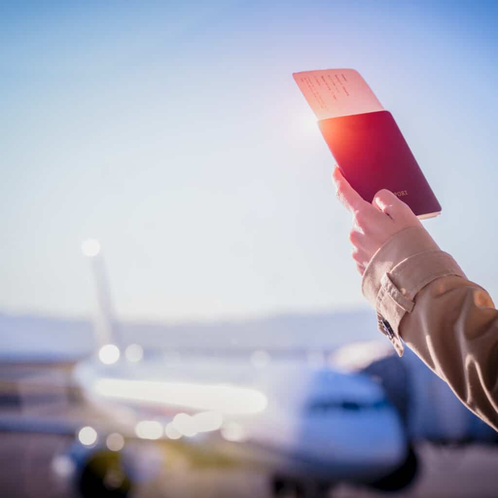 hand of woman passenger holding passport with boarding pass worry in delay of the flight in airport terminal transfer area, flight delay or misssing flight attention in disaster travel, stay in the transit area of the airport terminal, disaster or disappointment in traveling, awaiting for transit in airport, flight cancelled due to infection of COVID at destination